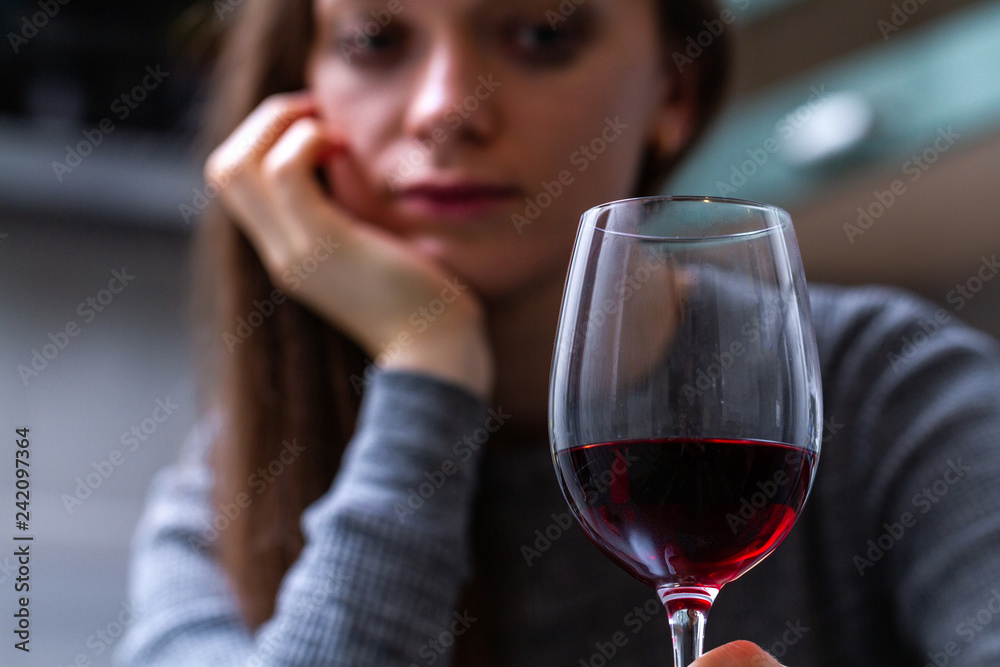 Depressed, divorced crying woman sitting alone in kitchen at home and drinking a glass of red wine because of problems at work and troubles in relationships. Social and life problems Depressed, divorced crying woman sitting alone in kitchen at home and drinking a glass of red wine because of problems at work and troubles in relationships. Social and life problems