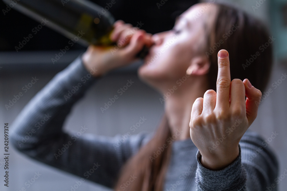 Depressed, divorced woman drinking red wine alone in kitchen at home. Female alcoholism concept. Protest in the treatment of alcohol addiction. Life problems