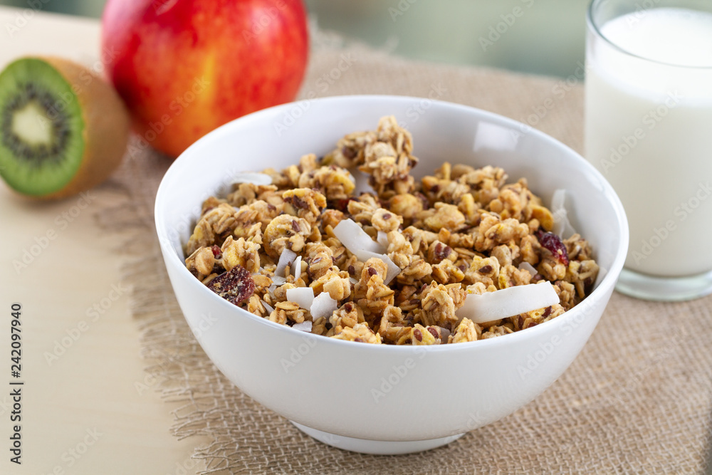 Dry breakfast cereals. Crunchy honey muesli bowl with flax seeds, cranberries and coconut and a glass of milk on a table. Healthy and fiber food. Breakfast time Dry breakfast cereals. Crunchy honey muesli bowl with flax seeds, cranberries and coconut and a glass of milk on a table. Healthy and fiber food. Breakfast time