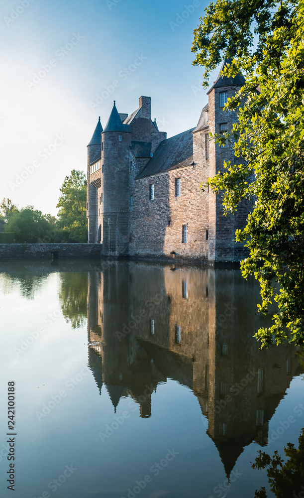 The turrets and drawbridge of the 14th century Chateau de Trecesson in the Forest of Paimpont viewed across the large pool by which it is surrounded