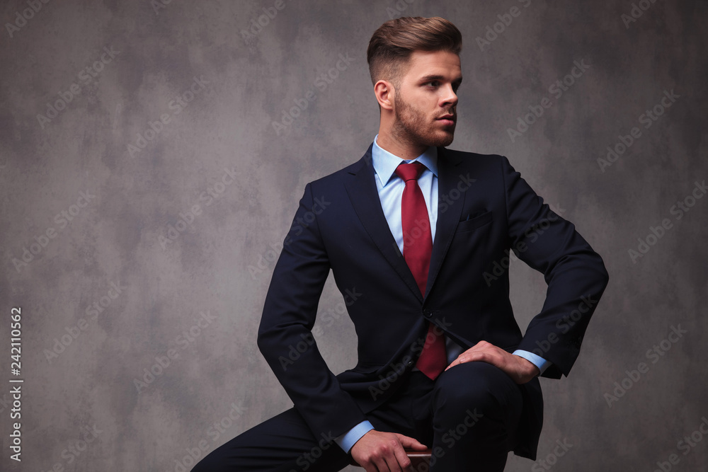 curious businessman sitting on wooden chair looks to side curious businessman sitting on wooden chair looks to side