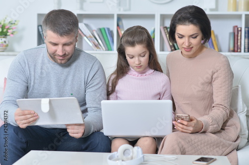 Happy parents and daughter using digital devices