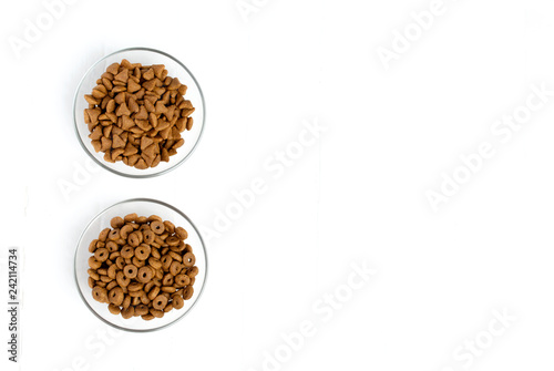 Dry cat food poured into a glass bowl on a white background