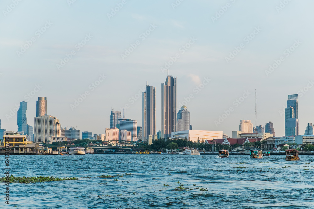 Naklejka premium Landscape view of buildings at the Chao Phraya riverside and boats in the river. Bangkok, Thailand.