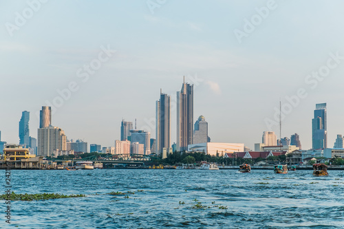 Landscape view of buildings at the Chao Phraya riverside and boats in the river. Bangkok, Thailand.