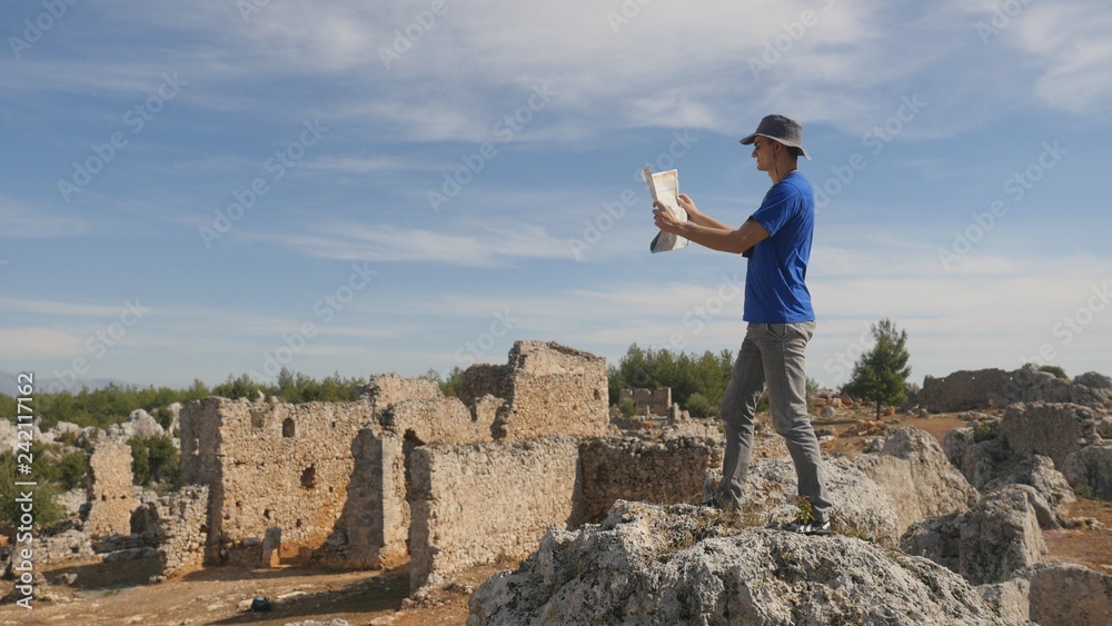 Naklejka premium Young man traveler with map exploring ancient city