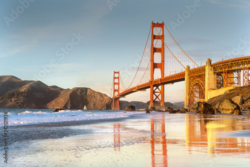 Golden gate bridge with reflections on water at sunset low tide time. 