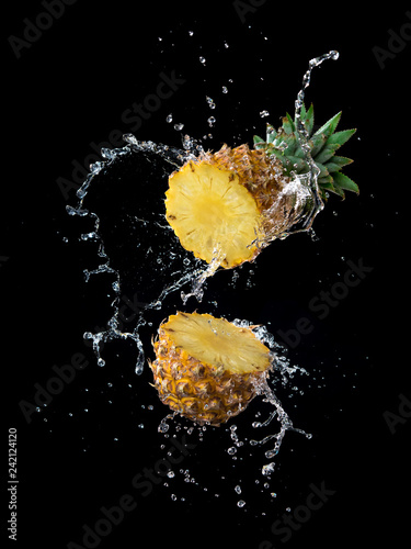 Slice of yellow pineapple with water splashing isolated on black background
