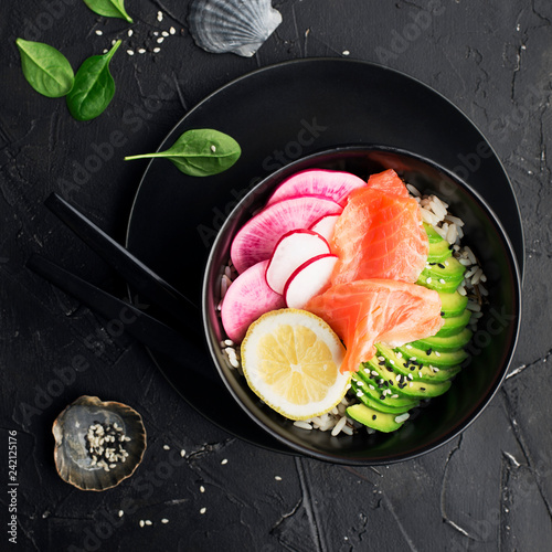 Fresh seafood meal. Poke gravlax bowl with salmon and avocado on a dark background. Top view.