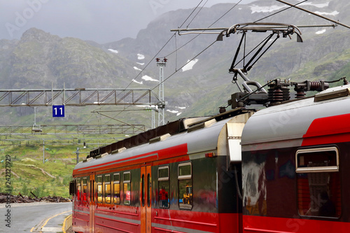 View of Voss mountain train stopped at Myrdal train station with snowy peaks on backgound, Norway.