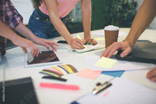 Picture of people working together at one table. They hold stickers and markers. Hands pointing. photo