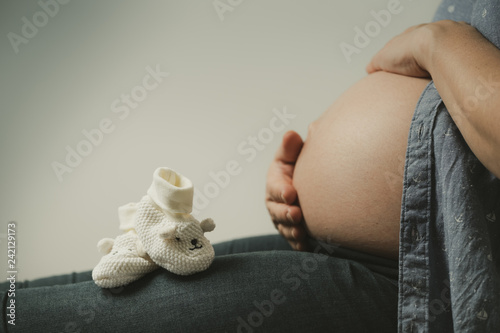 Babyschuhe vor nacktem Babybauch  photo