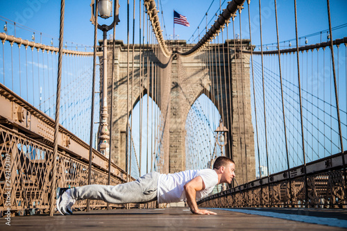 Young athlete doing pushups on Brooklyn Bridge in New York City © Stefan