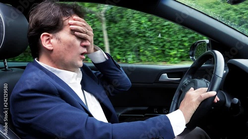 Man driving car not feeling well over stressed because of too much work