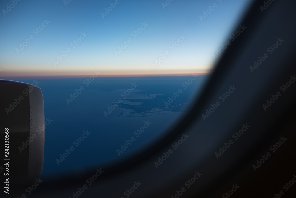 View from the window to airplane engine on runway of airport. Above the sky, on sunrise.