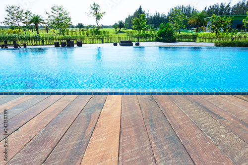 Beautiful blue water ,swimming pool for background and empty wood floor .Blank space for text and images.