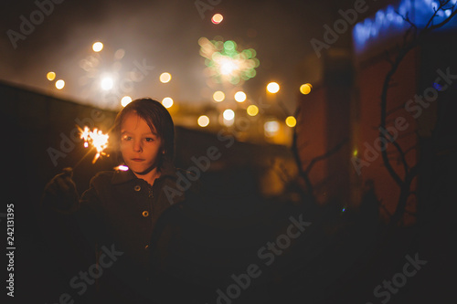 Waist up portrait of happy family celebrating New Year together and lighting sparklers outdoors