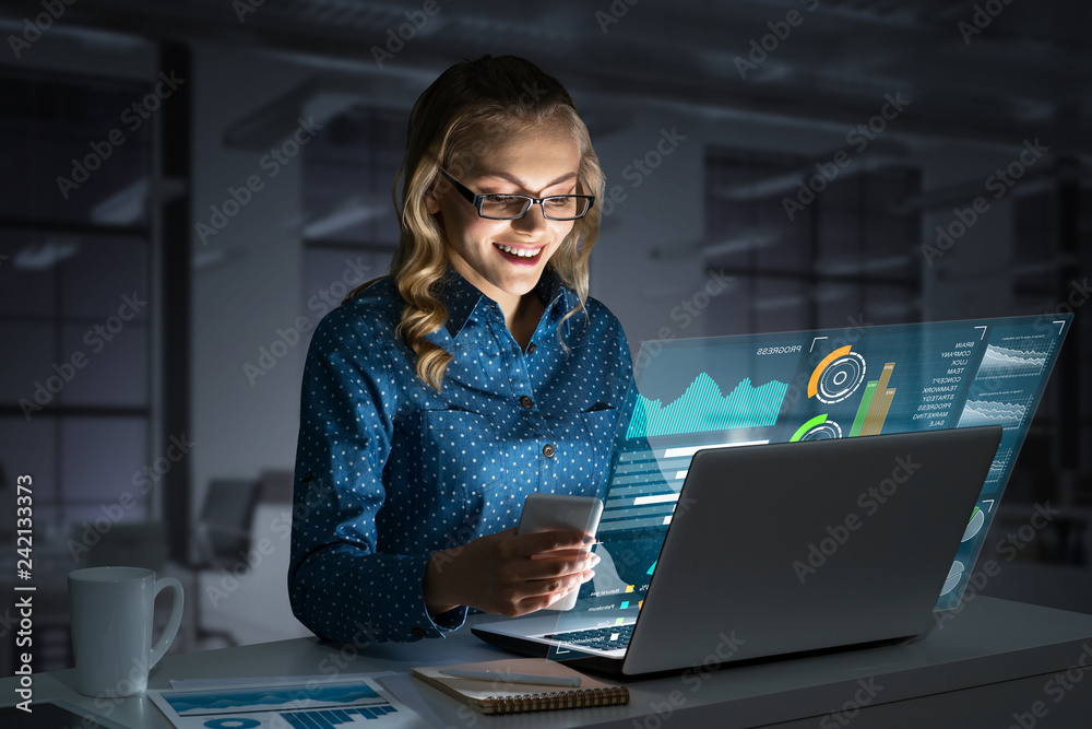 Beautiful blonde working on laptop and infographs out of screen. Mixed media Beautiful blonde working on laptop and infographs out of screen. Mixed media