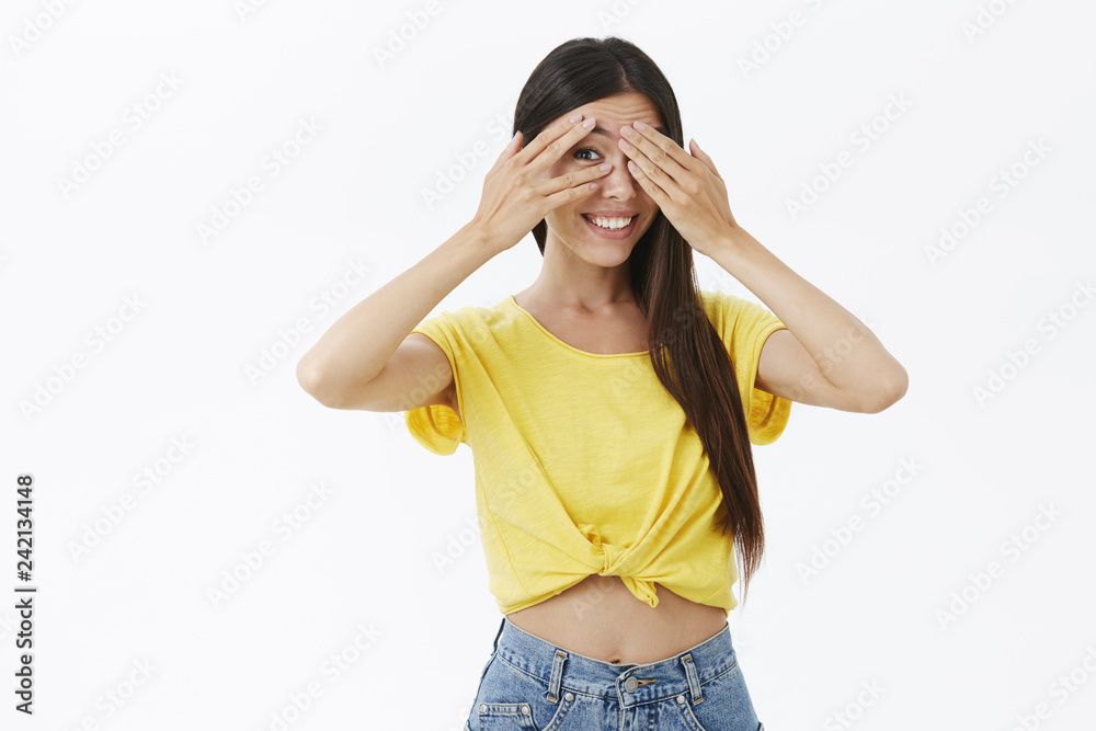 Waist-up shot of creative intrigued and joyful cute european female in trendy yellow t-shirt covering eyes with palms peeking through fingers interested and curious smiling with enthusiasm Waist-up shot of creative intrigued and joyful cute european female in trendy yellow t-shirt covering eyes with palms peeking through fingers interested and curious smiling with enthusiasm