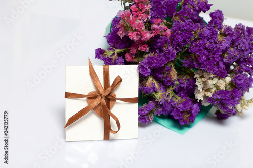 A bouquet of dried flowers, wrapped in colored paper. Near a small greeting card. On a white background.