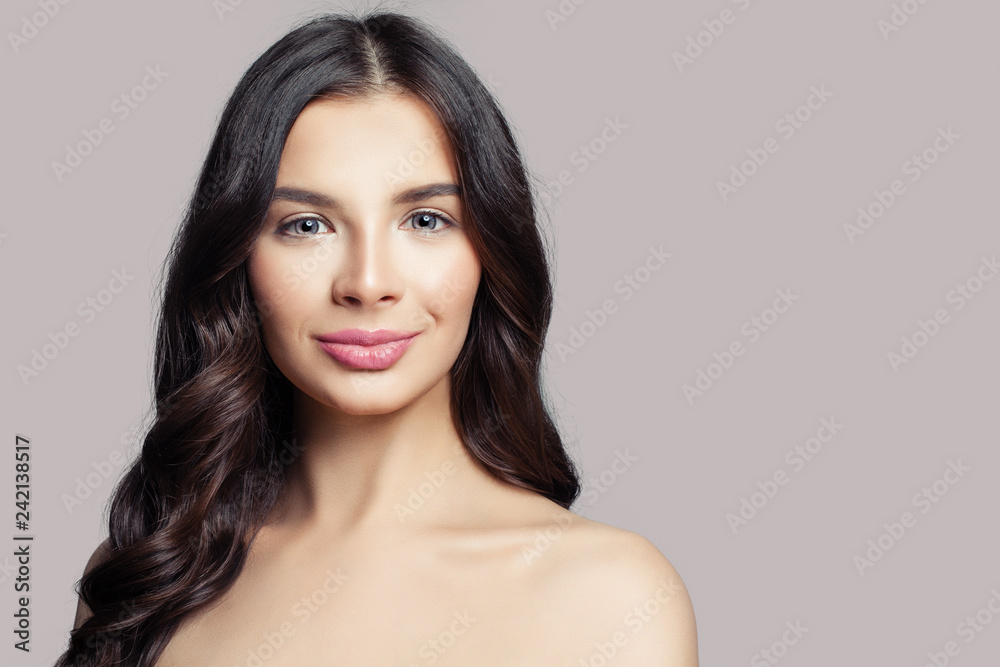Beautiful woman face. Smiling female model with long curly hair on pink background Beautiful woman face. Smiling female model with long curly hair on pink background
