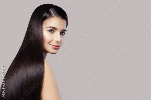 Beautiful woman with long straight hair and healthy skin on pink background