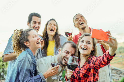 Group of happy friends taking selfie using mobile smart phone camera - Young people having fun a drinking red wine outdoor - Friendship, technology, youth lifestyle concept