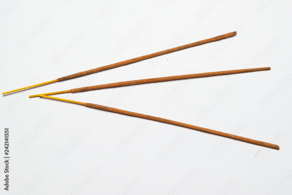 three Indian incense sticks on a solid light background three Indian incense sticks on a solid light background