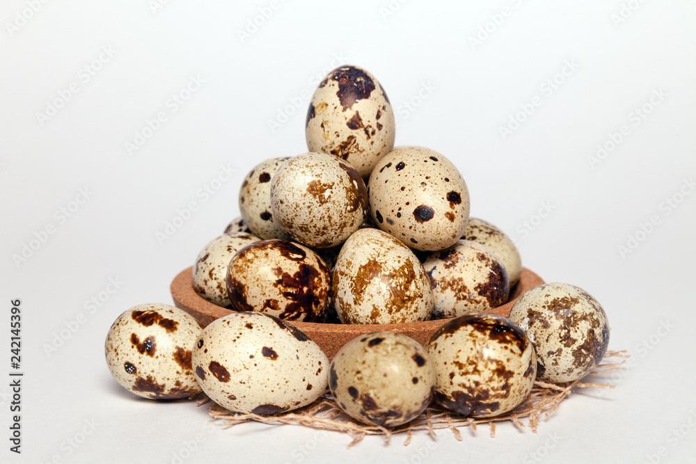 Closeup Easter small fresh textural quail eggs in round wooden bowl with textile isolated on white background. Concept traditional treat Orthodox Christian spring Church holiday. Free space, copyspace