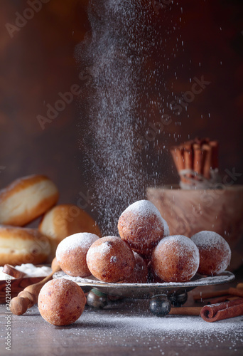 Various donuts powdered with sugar on a brown background.