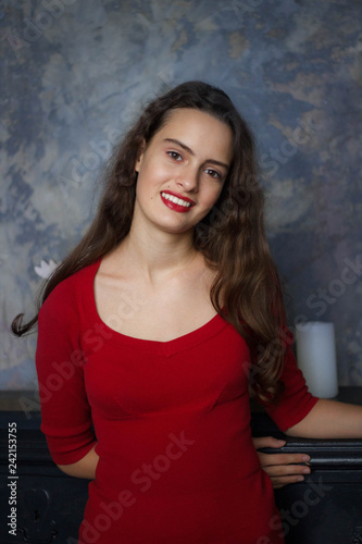 Smyling young girl in a red dress on a dark background