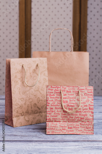 Kraft paper shopping bags. Three brown paper gift bags with printing, front view.