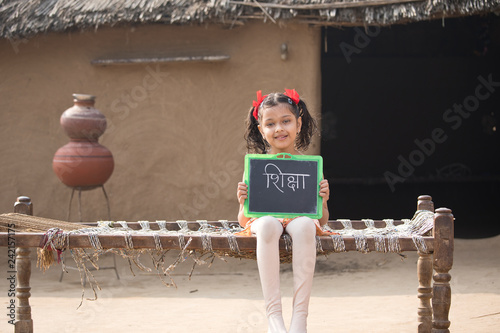 Rural Indian little girl holding slate at home