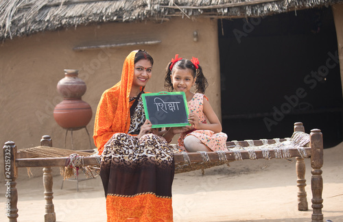 Mother with her daughter holding slate at village