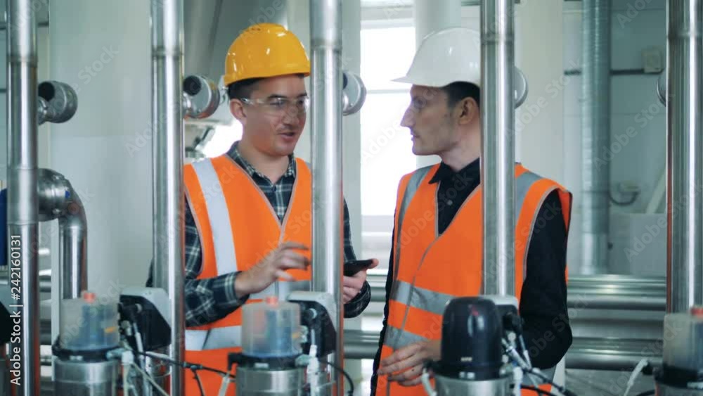 People talk while standing in a brewery facility, close up. People talk while standing in a brewery facility, close up.