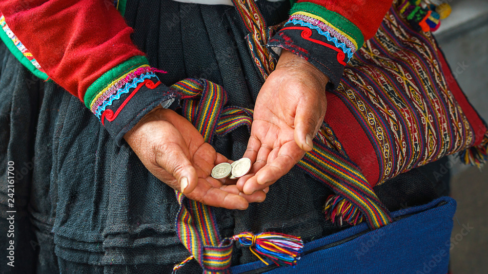 Hands of peruvian woman holding national coins metal sol. Close up of weaving and culture Peru, Cusco. woman dressed in colorful traditional native Peruvian closing in the market in Machu Picchu