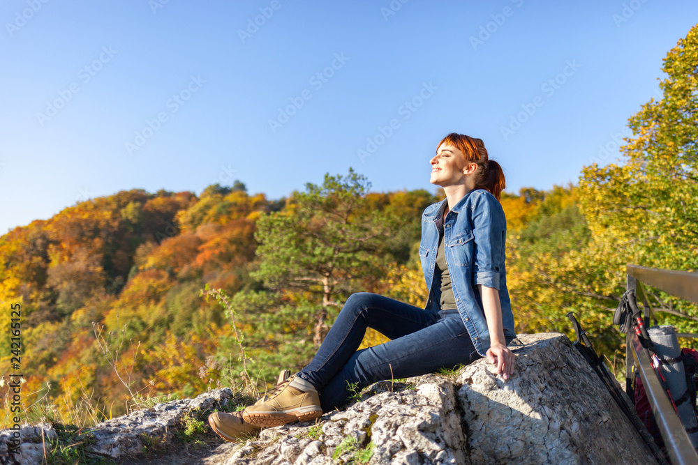 Traveler woman after trekking sitting on rock looking at mountain view