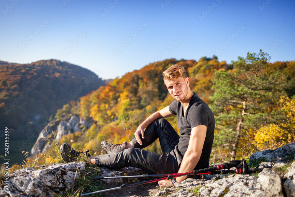 Traveler man after trekking sitting on rock looking at mountain view Traveler man after trekking sitting on rock looking at mountain view