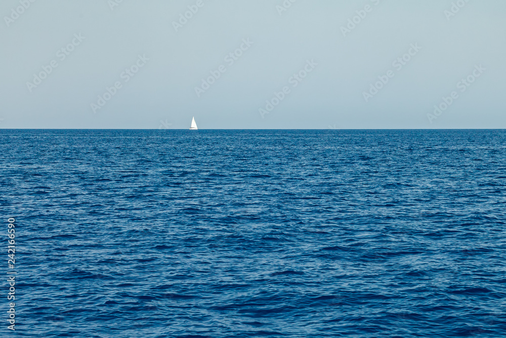 A lone white sailing yacht sails in the waters of the Mediterranean