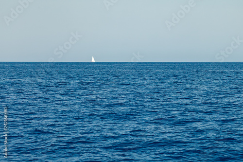 A lone white sailing yacht sails in the waters of the Mediterranean