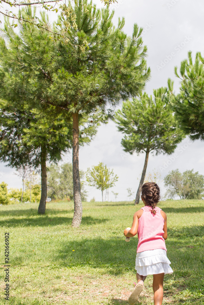 a little girl running through the trees in a park a little girl running through the trees in a park