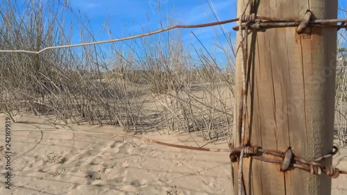 a Panning shot of an old wire fence on the beach. Shot on a warm summer day. photo