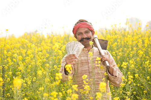 Farmer holding Indian Rupee notes in field