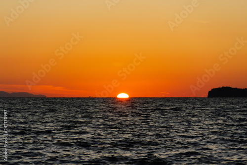 The sun is hiding the beach edge with orange sky