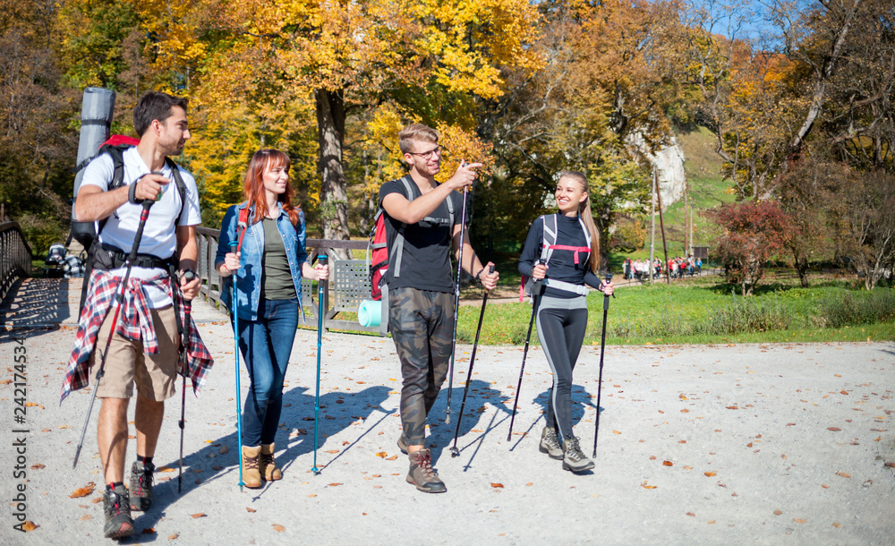 Authentic group of friends on tourist trip walking with backpacks and trekking sticks Authentic group of friends on tourist trip walking with backpacks and trekking sticks