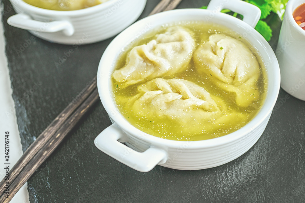 Asian dumplings in broth in a white bowl. Selective focus Asian dumplings in broth in a white bowl. Selective focus