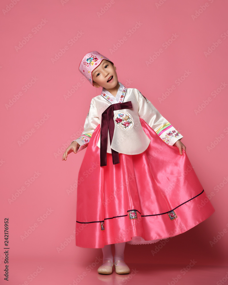 Korean little baby girl in traditional silk dress for new year celebration dancing on pink Korean little baby girl in traditional silk dress for new year celebration dancing on pink