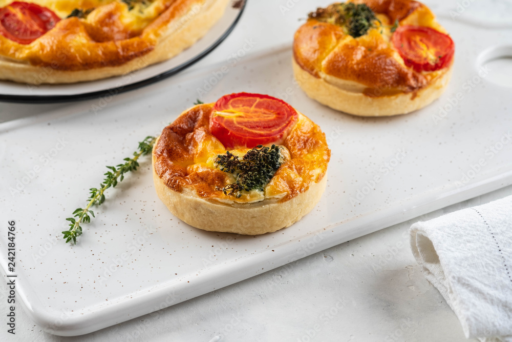 Vegetable pie quiche with broccoli, tomatoes and soft cheese on white background. Vegetable pie quiche with broccoli, tomatoes and soft cheese on white background.