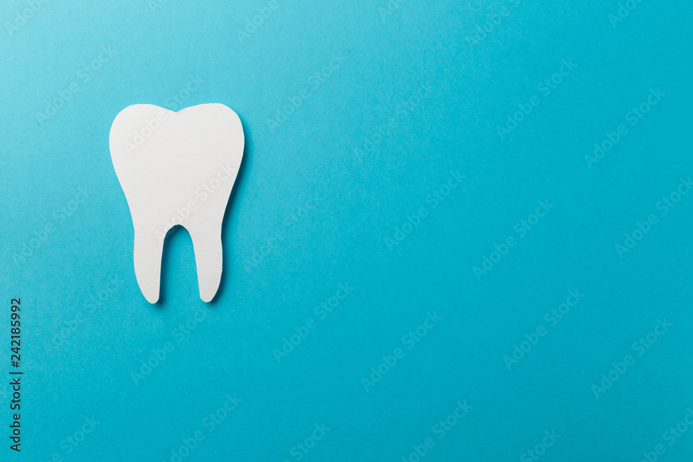 White tooth on blue background with copy space. Oral dental hygiene. Teeth whitening. Dental health concept. Oral care, teeth restoration. Dentist day concept. Flat lay. Top view. Pastel colors White tooth on blue background with copy space. Oral dental hygiene. Teeth whitening. Dental health concept. Oral care, teeth restoration. Dentist day concept. Flat lay. Top view. Pastel colors