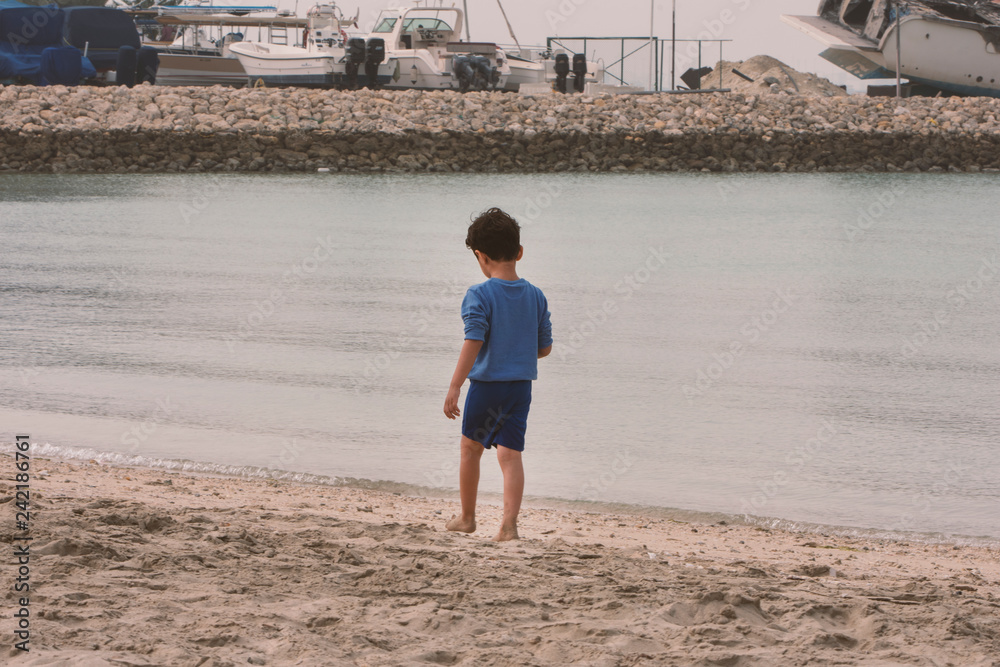 a Little boy on the beach walking on sands a Little boy on the beach walking on sands